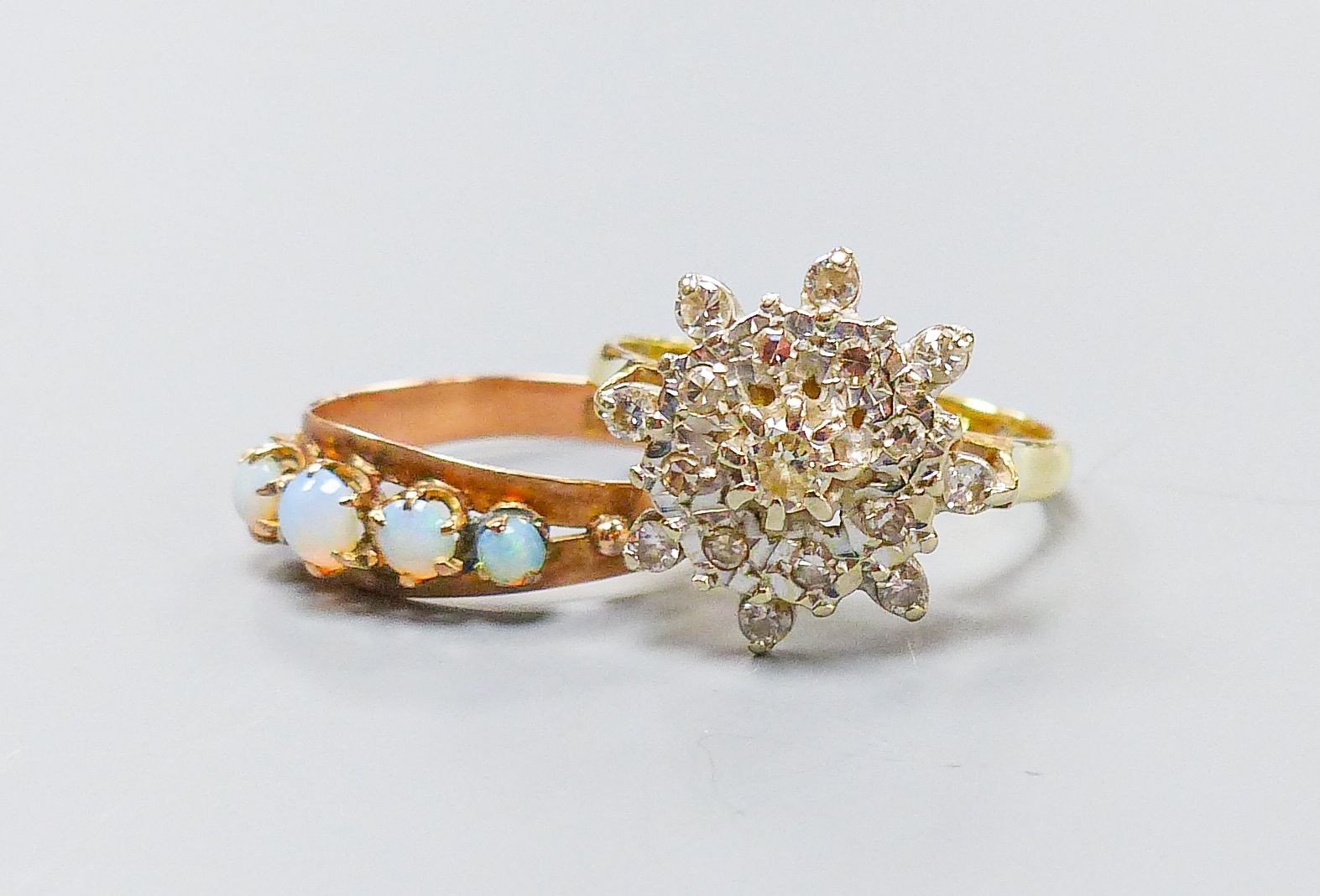 A yellow metal (stamped 9) and graduated five stone white opal set half hoop ring, size M, gross 1.2 grams and and 18ct gold and diamond chip cluster ring, gross 4.6 grams.